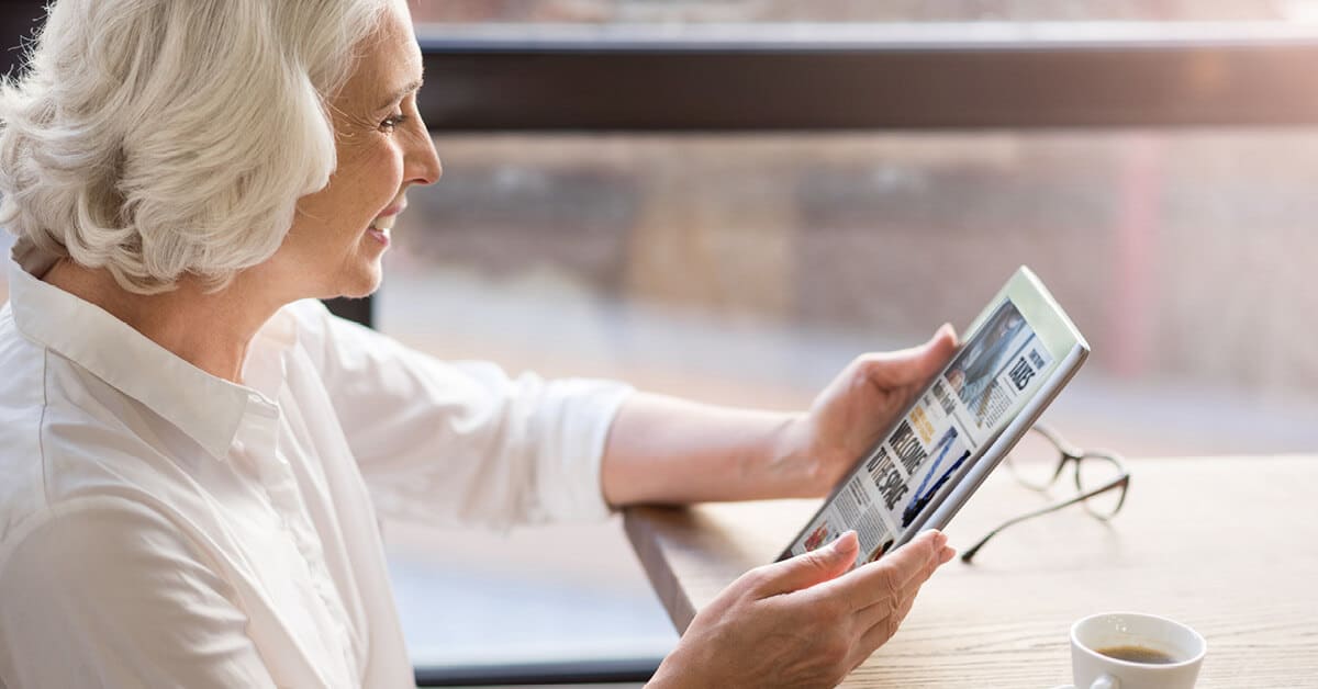 older woman reading the news on a tablet