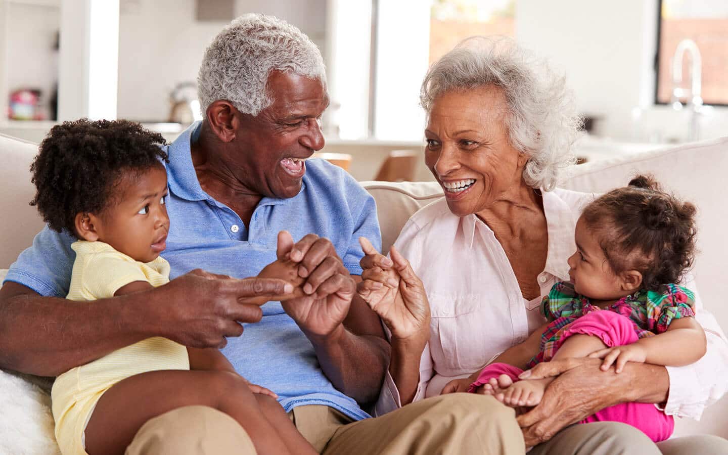 elderly couple laughing and playing with their grandbabies