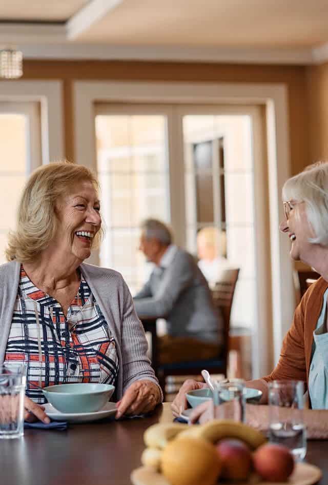 two older women smiling while eating breakfast
