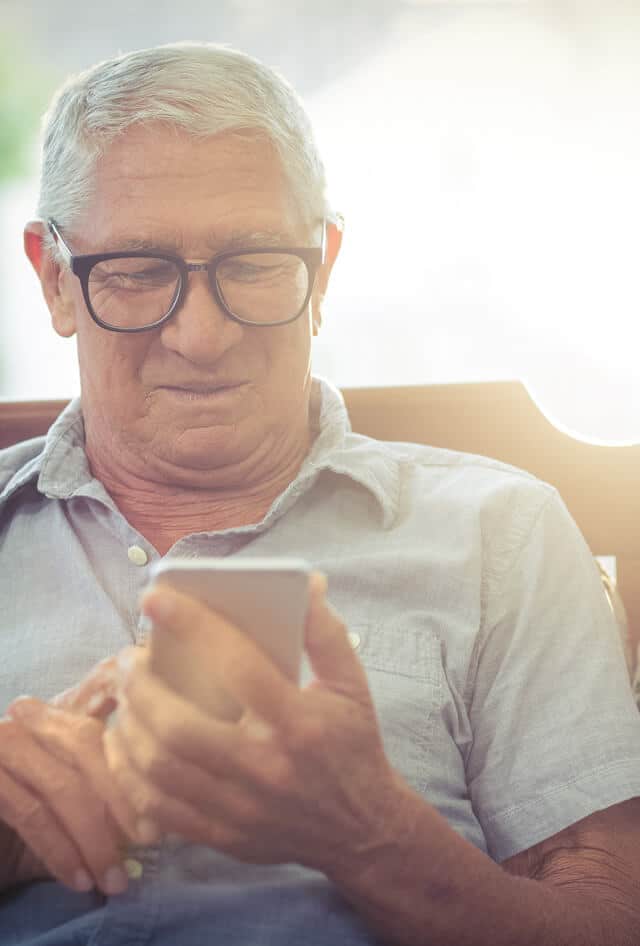 elderly man sitting and looking at his cell phone