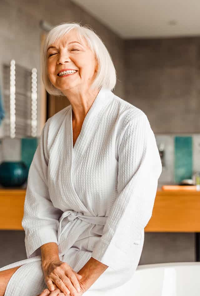 Senior lady dressed in white bath robe smiling